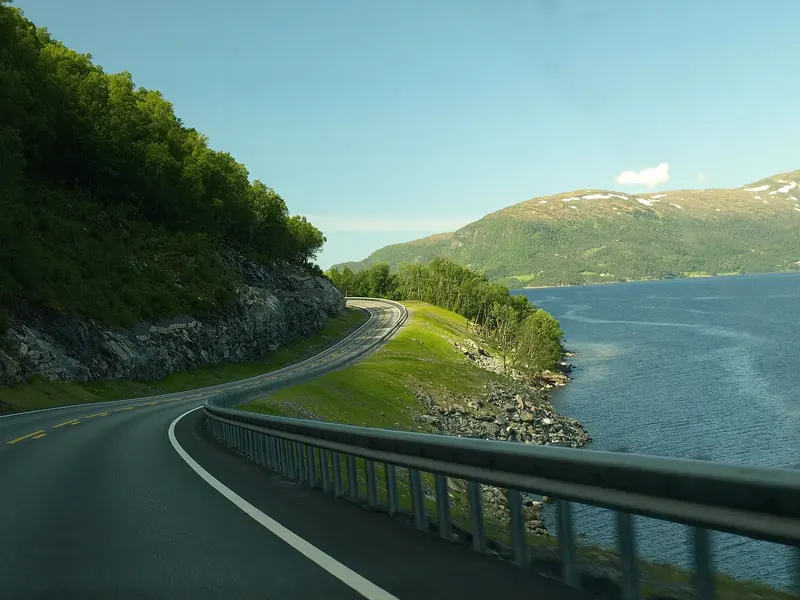 A winding hill road beside a lake in the mountains