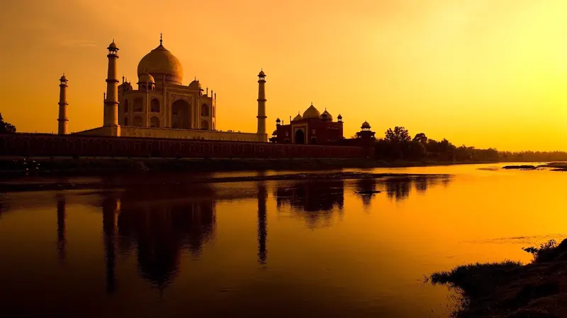 The Taj Mahal silhouetted at sunset across the Yamuna